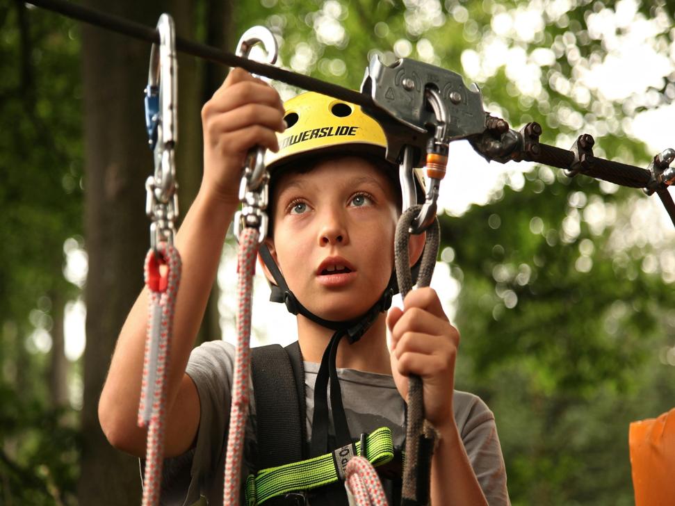 Young boy prepares to zip line through woods