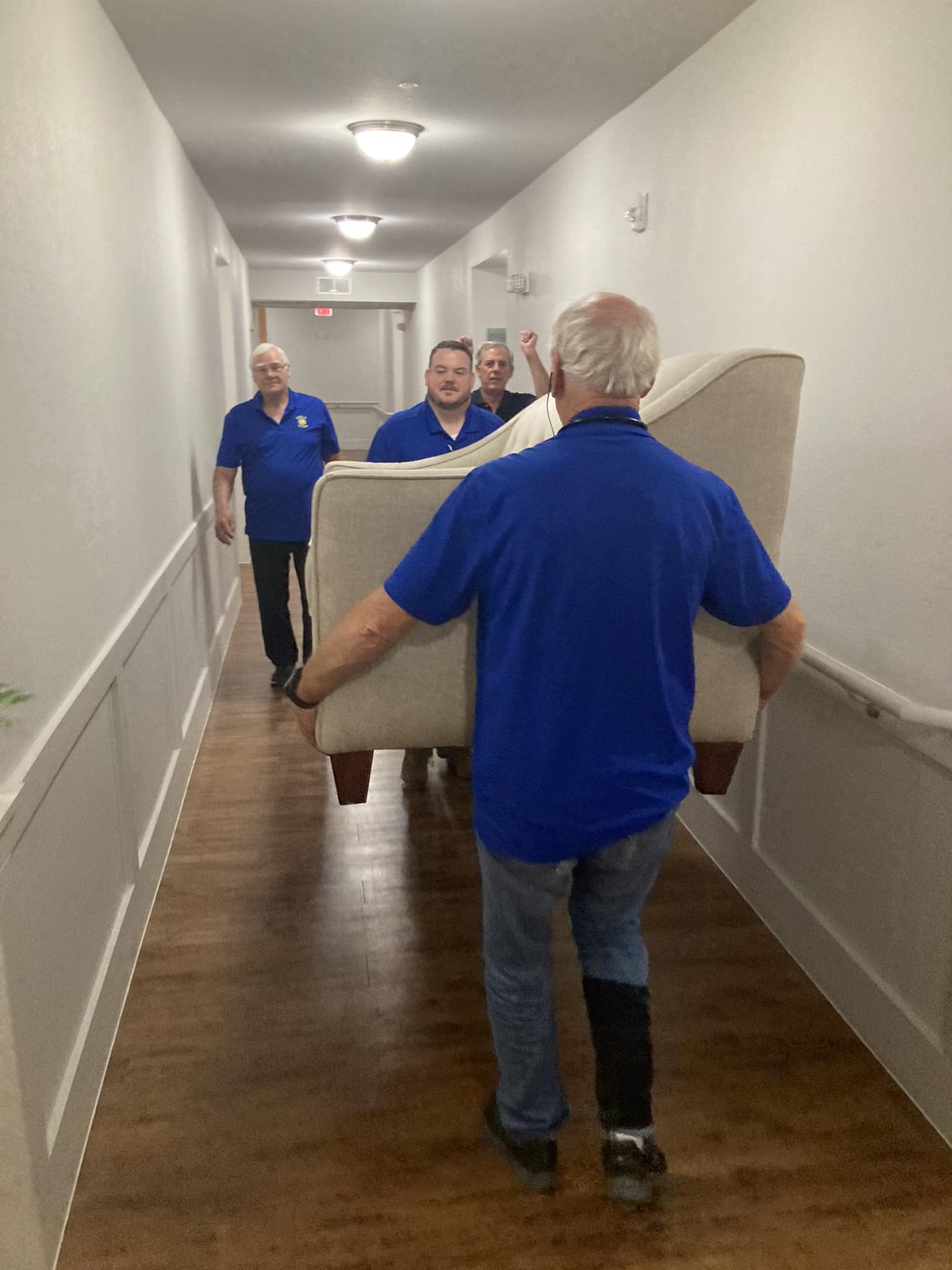 Several Lions Club members carry a couch down a hallway